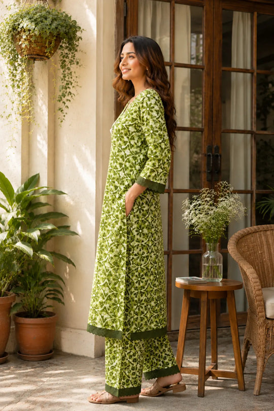 The outfit has a light olive green base with a darker green floral pattern and solid green trim., detail