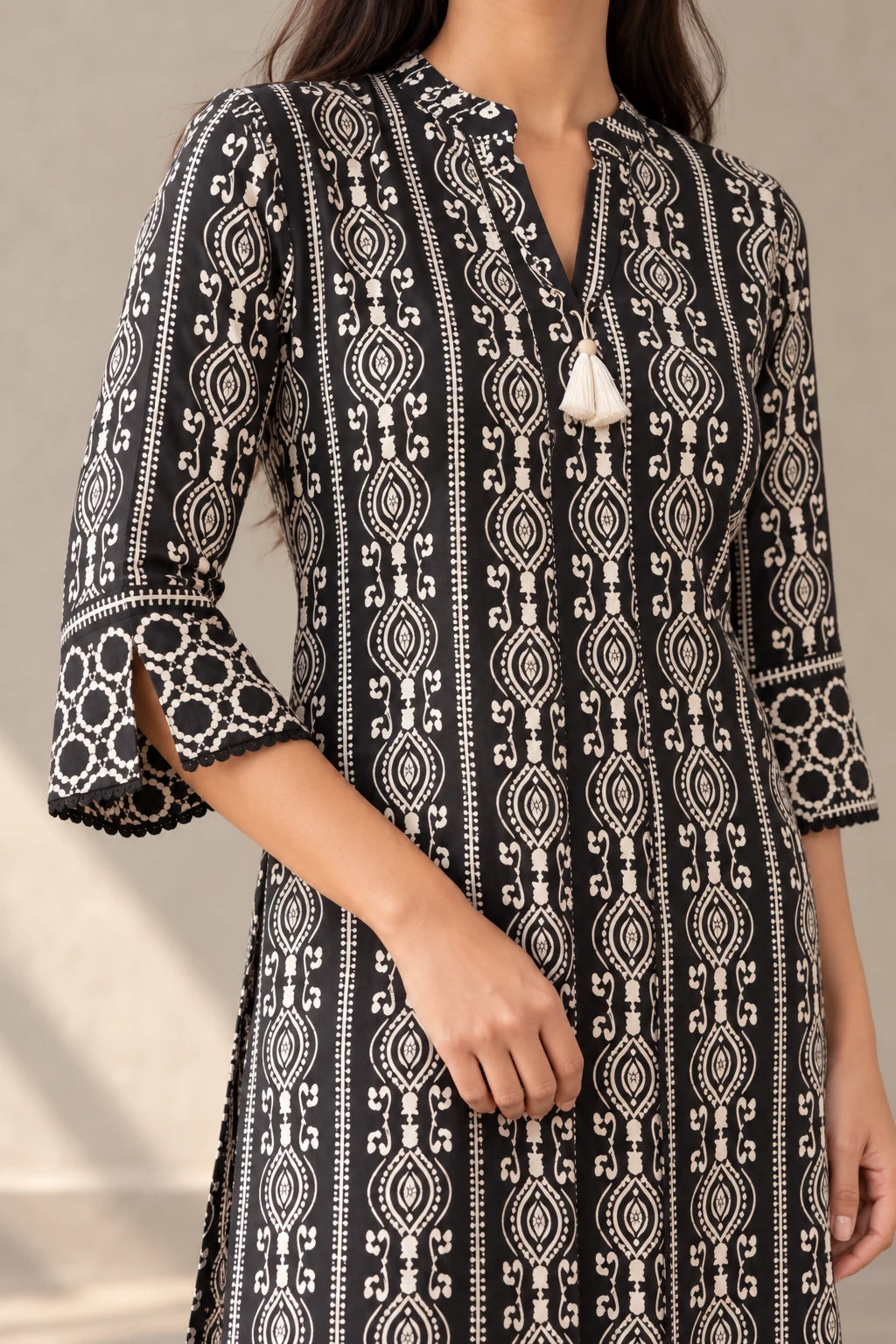 Close-up of the black batik kurta's mandarin collar, white tassel and slit printed cuff